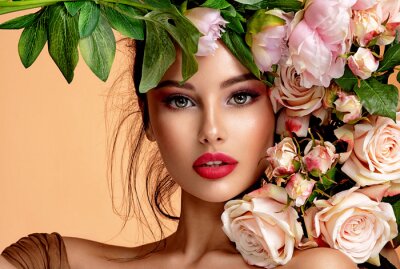 Fototapeta Beautiful white girl with flowers. Stunning brunette girl with big bouquet flowers of roses. Closeup face of young beautiful woman with a healthy clean skin. Pretty woman with bright makeup